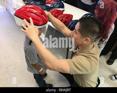 Hospital Corpsman 3. Klasse Thien Trinh, ein corpsman mit Naval Hospital Pensacola Neurologie, Orte einen Helm auf Ritter Moore, 5, um zu überprüfen, ob es richtig sitzt. Segler aus Naval Hospital Pensacola Neurologie und Hochschulabsolventen aus der Anker Klinik, eine lokale Verhaltensmedizin Klinik, besuchte N.B. Cook Volksschule in Pensacola, Fla., 4. März Helm Sicherheit zu fördern. Die Matrosen gab auch entfernt über 60 Helme für Kinder, solange Sie versprochen haben Sie zu tragen. Stockfoto