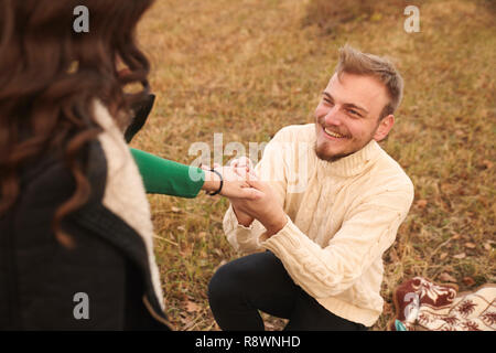 Junge lächelnde glücklicher Mann kniet, den jungen Frau, 20-29 Jahre alt, allein auf dem Feld. Herbst. Stockfoto
