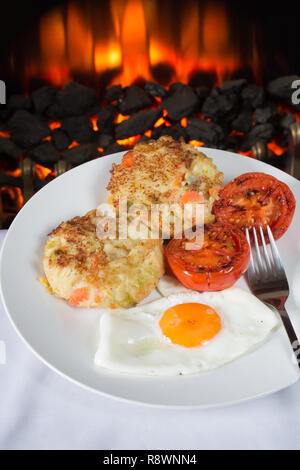 Ein traditionelles Gericht der übrig gebliebene Weihnachtsessen veg in Bubble und Squeak mit Spiegelei serviert und gegrillten Tomaten Stockfoto