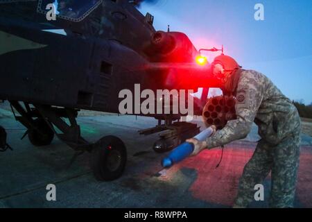 Ein Soldat von 1 Angriff Reconnaissance Battalion, 82nd Combat Aviation Brigade Bewaffnung Team, lasten Munition für die Wiederbewaffnung und Betankung Punkt auf einem AH-64D Apache Hubschrauber während einer Antenne schießwesen Übung, am Fort A.P. Hill, Virginia, März 13. Stockfoto