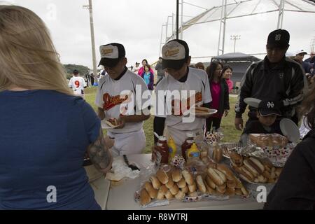 Okinawa Diamond Spieler erhalten Essen während ein potluck März 18 an Bord Camp Foster, Okinawa, Japan. Der Okinawa Diamant und Okiboys standen sich in einem Doppelspiel und nahm eine Pause zwischen den Spielen für das Essen. Die Eltern der Okiboys Baseball Team bewirtet ein potluck für die Spieler, der Trainerstab und die Familienangehörigen der beiden Mannschaften. Die Jungs saßen zusammen auf den Zuschauertribünen, Essen und unterhalten. Sie scherzten Miteinander, zu sehen, wer ein Würstchen essen und trinken eine Flasche Wasser am schnellsten. Der Okinawa Diamond Baseball Team ist von Naha, Okinawa, Japan. Stockfoto