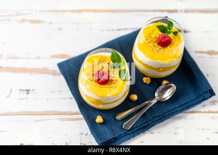 Mango und Ananas Smoothie mit Joghurt in zwei Gläser auf weißem Holztisch Stockfoto