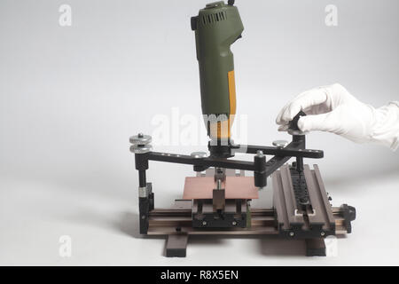 Arbeiter Hände an Gravur Gerät Stromabnehmer mit CNC-graveur mit Buchdruck Alphabet auf weißem Hintergrund Stockfoto