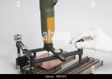 Arbeiter Hände an Gravur Gerät Stromabnehmer mit CNC-graveur mit Buchdruck Alphabet auf weißem Hintergrund Stockfoto