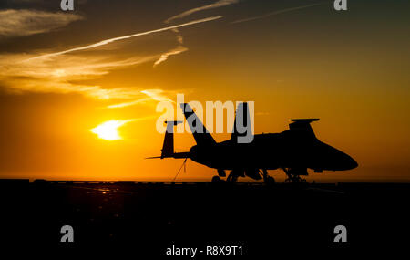 181202-N-LX 838-0098 ATLANTIK (31. 2, 2018) die Sonne hinter einer F/A-18C Super Hornet auf dem Flugdeck an Bord der Flugzeugträger USS George H.W. Bush (CVN 77). GHWB ist unterwegs in den Atlantischen Ozean die Durchführung von routinemäßigen Übungen Träger bereit zu halten. (U.S. Marine Foto von Mass Communication Specialist Seaman Steven Edgar) Stockfoto