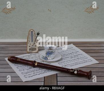 Englisch Teetasse und Untertasse mit floralem Dekor und Silber Felge, Metronom für Musik und einen Block Flöte auf einem Blatt von Musik Stockfoto