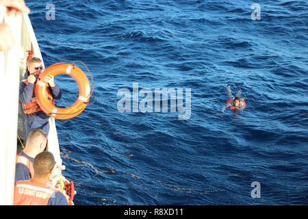 Die Crew der Coast Guard Cutter Joseph Tezanos rettet ein Überlebender eines Migranten gekenterte Boot am Nachmittag des Dez. 6, 2018, in Wasser nur aus Isla Saona, Dominikanische Republik. Die Crew der kommerziellen Tanker Meer Board Ranger gerettet 20 Sonstige Migranten nach Anfahren des Gekenterten Schiffes früh in den Morgen. Coast Guard Rettung Mannschaften weiterhin Dez. 8, 2018 für sieben weitere Migranten, die angeblich auch an Bord des Gekenterten Schiffes waren zu suchen. Stockfoto