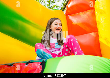 Gerne kleine Mädchen haben viel Spaß auf der Hüpfburg beim Einschieben. Stockfoto