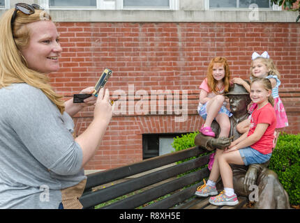 Eine Frau, die Fotos ihrer Kinder mit einer Bronzestatue von William Faulkner, 31. Mai 2015, in Oxford, Mississippi. Stockfoto