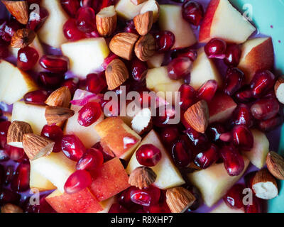 Blick von oben auf die leckeren Schüssel mit Granatapfel, Apfel und Mandeln Stockfoto