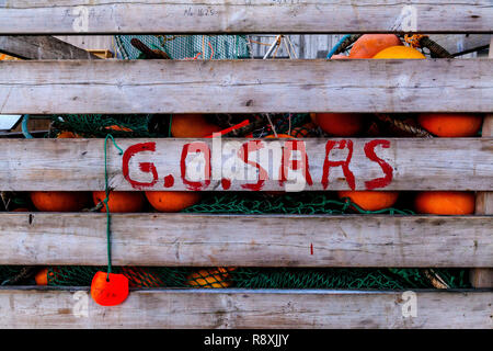 Holzkiste mit Haufen von Rot und Orange angeln Bojen und grünen Fischernetze, auf einem Kai im Hafen von Bergen, Norwegen Stockfoto