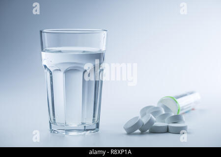 Magnesium Tabletten und Tasse Wasser Blau auf weißem Hintergrund. Stockfoto
