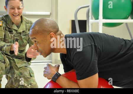 Physiotherapeuten, US-Armee Kapitän Lindsay B. Gordon, Links, beauftragt das Kommando und General Staff College Student, U.S. Army Maj. Calvin "Quake" Peterson auf die korrekten Techniken für die Stärkung der Core mit einem Gymnastikball. Die Executive Wellness Physikalische Therapie Programm personalisiert Programme für Studierende körperliche Stärke und Flexibilität, Munson Armee Health Center, Fort Leavenworth, 1. März 2017 zu verbessern. Stockfoto