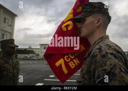 Sgt. Samuel Kornett hält die Firma Farben während der Verteidigung Cyberspace Betrieb interner Verteidigungsmaßnahmen Firma Zeremonie im Camp Hansen, Okinawa, Japan, Dez. 7, 2018. Oberstleutnant Michael Hlad, bataillonskommandeur des 7. Kommunikation Bataillon, diente als Offizier während der Zeremonie zu überprüfen. DCO-IDM-Unternehmen ist in erster Linie III MEF's Information Group der Verteidigung gegen Cyberangriffe in der indopazifischen Region. Cornet ist eine defensive cyber Operator mit DCO-IDM, 7. die Kommunikation Bataillon, III Marine Expeditionary Force Information Group. Stockfoto