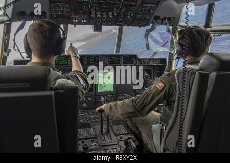 Kapitän Kaleb, Cole, 36th Airlift Squadron Flugzeuge Commander aus Yokota Air Base, Japan, Links, leitet Kapitän Laura Dempster, 36 als Pilot, während einer Praxis airdrop während des Betriebs Weihnachten Drop 2018 bei Andersen Air Force Base, Guam, Dez. 6, 2018. OCD bietet die US Air Force die Gelegenheit, neben der internationalen Partner zu trainieren und gleichzeitig kritische Versorgung 56 Mikronesischen Inseln. Stockfoto