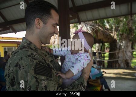 TRUJILLO, Honduras (31. 6, 2018) - Lt Eric Sulava, von Leechburg, Pa, hält eine junge Patientin mit einer von zwei medizinische Websites. Das Hospitalschiff USNS Comfort (T-AH20) ist auf einer 11-Woche medizinische Unterstützung Mission in Zentral- und Südamerika als Teil des US Southern Command's Enduring Promise Initiative. Arbeiten mit Gesundheit und Regierung Partner in Ecuador, Peru, Kolumbien und Honduras, die EINGESCHIFFTEN medizinisches Team kümmert sich an Bord und an Land-basierte medizinische Websites, wodurch der Druck auf die nationalen medizinischen Systeme zu entlasten, zum Teil durch eine Zunahme der grenzüberschreitenden Migranten. Die Bereitstellung Ref. Stockfoto