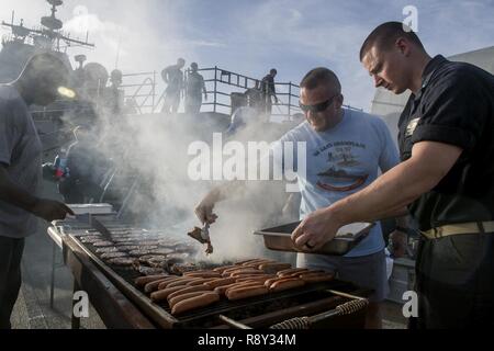 Pazifik (Feb. 26, 2017) Kapitän Chris Cegielski, kommandierender Offizier der Ticonderoga-Klasse geführte-missile Cruiser USS Lake Champlain (CG57), kocht das Essen auf der fantail während einer Stahl Picknick am Strand. Lake Champlain ist in regelmäßigen Western Pacific Bereitstellung mit der Carl Vinson Carrier Strike Group als Teil der US-Pazifikflotte-Initiative die Befehls- und Steuerfunktionen der USA 3 Flotte in der Indo-Asia zu verlängern - Pazifik Region. Navy Flugzeugträger Streik Gruppen haben die Indo-Asia - Pazifik regelmäßig und routinemäßig Seit mehr als 70 Jahren patrouillierte. Stockfoto