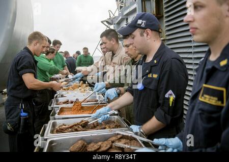 Pazifik (Feb. 26, 2017) Segler sind Lebensmittel auf den fantail der Ticonderoga-Klasse geführte-missile Cruiser USS Lake Champlain (CG57) während einer Stahl Picknick am Strand serviert. Lake Champlain ist in regelmäßigen Western Pacific Bereitstellung mit der Carl Vinson Carrier Strike Group als Teil der US-Pazifikflotte-Initiative die Befehls- und Steuerfunktionen der USA 3 Flotte in der Indo-Asia zu verlängern - Pazifik Region. Navy Flugzeugträger Streik Gruppen haben die Indo-Asia - Pazifik regelmäßig und routinemäßig Seit mehr als 70 Jahren patrouillierte. Stockfoto