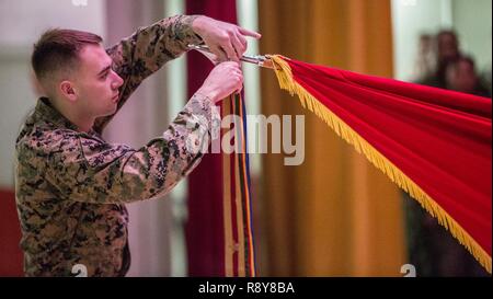 Us Marine mit 3d Marine Division, 4 Marine Regiment legt eine Schlacht Streamer an der Einheit guidon im 4. Marine Regiment 103 Schlacht Farben Umwidmung und Preisverleihung am Camp Schwab, Okinawa, Japan, 9. März 2017. Us-Marines, Matrosen, und Zivilisten in der Zeremonie nahm auf 103 Jahre Leistungen vom 4. Marine Regiment als die "älteste" und der "stolzesten" Regiment in den Korps zu reflektieren. Stockfoto