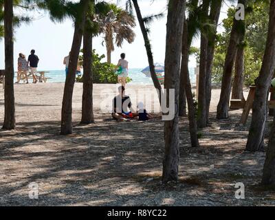 Vater und Kind Tochter im Schatten sitzen neben einem Key West Beach, Florida, USA. Stockfoto