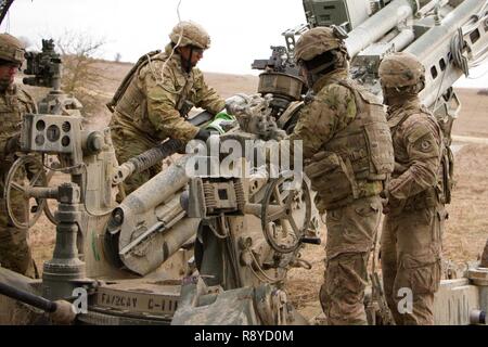 Spc. Christopher Rios (Mitte), #2 Mann für die gun Crew der 1. Abschnitt 1 Platoon, Cobra, Batterie, Field Artillery Squadron, 2d-Cavalry Regiment, US Army, Orte der Pulverladung in eine M777A2 Howitzer bei einem Brand Mission vom 8. März 2017 in Grafenwöhr Training Area, Deutschland. Das Geschwader nahmen an Dynamic Front II März 6-9, 2017. Die Übung aktiviert, den USA, Deutschland und der Tschechischen Republik gemeinsam ihre Artillerie Fähigkeiten zu synchronisieren. Stockfoto