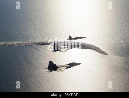 Ein paar F-22 Raptors mit der 95Th Fighter Squadron und ein T-38 Talon mit der 2 Fighter Training Squadron, Tyndall Air Force Base, Fla., fliegen in Formation entlang der "Vergessenen Küste" der Florida Panhandle, wie sie nach Durchführung von Schulungen über den Golf von Mexiko, 9. März 2017. 2. stellt FTS routinemäßig die 95th FS mit Luft-zu-Luft-Bedrohung der Replikation in Unterstützung des F-22 bekämpfen und formale Ausbildung. Stockfoto