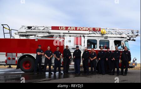 Mitglieder von Buckley Feuerwehr Posieren vor der P-33 Drehleiter Fahrzeug März 8, 2017, an der BFD auf Buckley Air Force Base, Colo. Die meisten Einrichtungen, die Buckley AFB sind mit Metall Dächer bei einem Steileren hang Schnee und Eis zu verhindern. In einem Leiter, der sich 75-Fuß bietet die Feuerwehrmänner eine sichere Plattform aus zu arbeiten. Stockfoto
