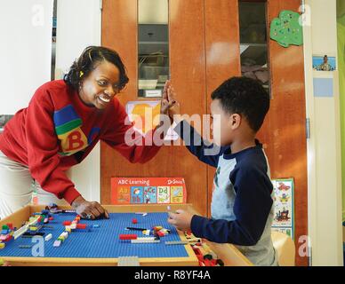 Fort Lee Child Development Center Anbieter Dannetter Braun, ein Kinder- und Jugendprogramm Assistant, gibt eine fünf bis Kaiden Hilliard für eine gute Wahl zu einem Anteil auf ein Spielzeug zum 13. März in Yorktown CDC Starke Anfänge Klassenzimmer. Stockfoto