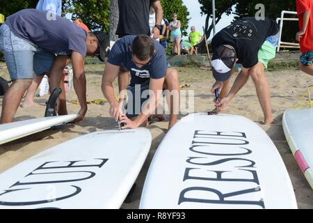 Us-Küstenwache im 14. Bezirk von der Küstenwache zusammenbauen Surfboard fins während einer AccesSurf Veranstaltung in White Plains Strand, Oahu, 15. März 2017. Besatzungsmitglieder freiwillig verwundete Veteranen durch die AccesSurf Programm zum Surfen zu unterrichten. Stockfoto