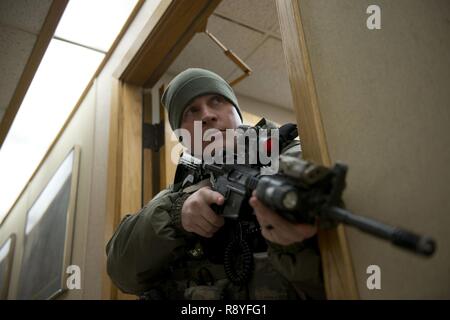 Air Force Staff Sgt. Nicholas Woolridge, ein streifenpolizist mit der 673 d Security Forces Squadron Uhren der Flur als seine Mitarbeiter löscht den nächsten Raum in der 773Rd Bauingenieur Squadron, März 13. Die Sicherheitskräfte Geschwader auf gemeinsamer Basis Elmendorf-Richardson führt regelmäßig keine - Bekanntmachung der Tests der aktiven shooter Mentalitäten Büros' um. Stockfoto