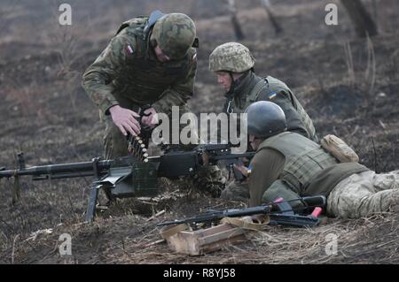 Eine polnische Armee Kursleiter eine Rückmeldung an ukrainische Soldaten der 1.Bataillon, 28 mechanisierte Infanterie Brigade auf, wie man richtig einen DShK Heavy Machine Gun während einer Live-fire Übung in der yavoriv Combat Training Center auf der internationalen Friedenssicherung und Security Center laden, in der Nähe von yavoriv, der Ukraine, der am 16. März. Die live-fire Übung ist Teil eines Blockes der Anweisung von ukrainischen Combat Training Center Personal unterrichtet, die durch Mitglieder des Gemeinsamen multinationalen Ausbildung Group-Ukraine betreut werden. JMTG-U ist eine Koalition aus servicemembers aus Kanada, Dänemark, Litauen, Po Stockfoto