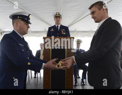 Barret Christoper Loux, das grosse - Urenkel von Lawrence Lawson, Namensgeber der Coast Guard Cutter Lawrence Lawson, Hände eine lange Glas Petty Officer First Class Steven Endicott, als Teil einer naval Tradition während der Inbetriebnahme in Cape May, New Jersey, 18. März 2017. Die Lawrence Lawson ist die zweite 154-Fuß-Sentinel Class Cutter in der Mittelatlantischen Region stationiert zu werden und wird eine Vielzahl von Missionen aus North Carolina nach New Jersey. Stockfoto