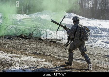 Ein Fallschirmjäger zu einem Unternehmen zugewiesen sind, 6. Brigade Engineer Battalion, 4th Infantry Brigade Combat Team (Airborne), 25 Infanterie Division, U.S. Army Alaska, hetzt einen Sprengsatz auf einem Hindernis zu setzen, während die Durchführung von Live-Fire Training am Infanteriezug Schlacht Kurs auf gemeinsamer Basis Elmendorf-Richardson, Alaska, 17. März 2017. Die Ausübung geschliffen Infanterie Fähigkeiten die Fallschirmjäger' wie Platoon Bewegung und Kommunikation, Hindernis gegen und die Erfassung objektiver durch Angriff und Manöver. Stockfoto