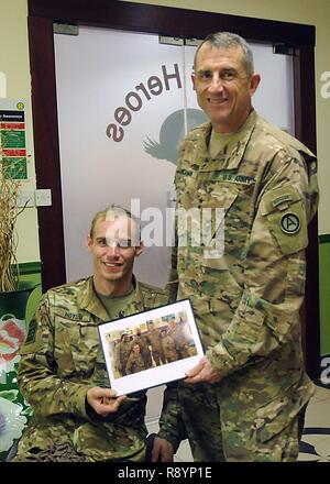 Generalmajor William Hickman (rechts), Stellvertretender kommandierender General für die US-Army Central, präsentiert ein Foto für die pensionierten Sgt. Wird Hoyum, 1. Brigade, 82nd Airborne Division, nach einem Abendessen für den Betrieb Ordentliche Soldaten hielten, 19. März Camp Arifjan, Kuwait. Hoyum ist einer von sechs Soldaten, die in dieser Runde der OPE, das ist ein Programm, dass die Krieger, die auf dem Schlachtfeld verwundet bringt und anschließend erlaubt Ihnen, "ordnungsgemäß verlassen, "Theater teil. Ein Improvised Explosive Device Hoyum von der Brust abwärts gelähmt, während er in Afghanistan diente, Juni 2012. Stockfoto