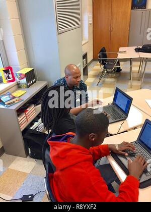 FT JACKSON, SC (15. März 2017) Cmdr. Leroy Junge, zugeordnet zu den Naval Seelsorgestelle Schule und Center (NCSC), unterstützt die siebte Klasse Schülerinnen und Schüler mit einem Computer mathe Programm in der Vorbereitung für den anstehenden landesweiten Tests während die Afterschool Programm an Alcorn Middle School in Columbia, South Carolina. U.S. Navy Stockfoto