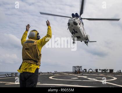 Gewässer südlich von Japan (16. März 2017) der Bootsmann Mate Seaman Christopher Bühler Signale eine SA330 Puma Helikopter auf dem Flugdeck der Arleigh Burke in Land-Klasse geführte Anti-raketen-Zerstörer USS Barry (DDG52) während einer Auffüllung-auf-See. Barry ist auf Patrouille in Gewässern südlich von Japan Unterstützung der Sicherheit und Stabilität in der Indo-Asia-Pazifik-Region. Stockfoto