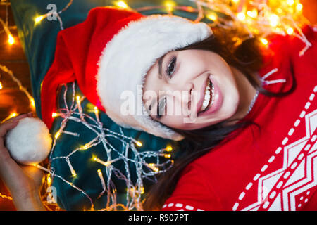 Nahaufnahme Porträt der Frau in der Weihnachtsbeleuchtung auf dem Boden zu Hause liegend verpackt Stockfoto