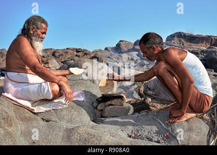 Orchha, Madhya Pradesh, Indien - 20. Oktober 2018: Indische Frühstück. Hindu mans Vorbereitung chapati auf offenem Feuer in den lokalen Dorf. Chapati als tra Stockfoto