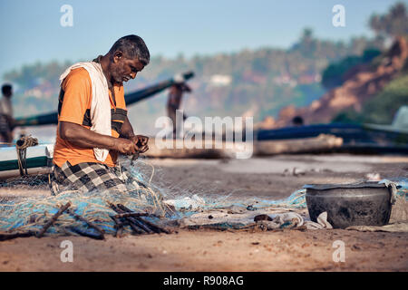 Cochin, Kerala, Indien - 30. November 2017. Ein nicht identifiziertes indische Fischer, wird Fisch aus dem Fischernetz. Angeln am Strand von Varkala. Stockfoto