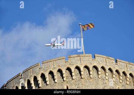 Ein Flugzeug aus London Heathrow Airport führt über den Bergfried von Schloss Windsor, mit dem Royal Standard fliegen. Stockfoto