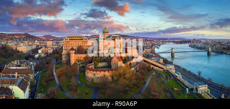 Budapest, Ungarn - goldener Sonnenaufgang an der Budaer Burg Königspalast mit Széchenyi Kettenbrücke, Parlament und bunten Wolken Stockfoto