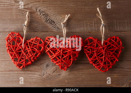 Red rattan Herzen hängen an alten Zaun am Valentinstag Stockfoto