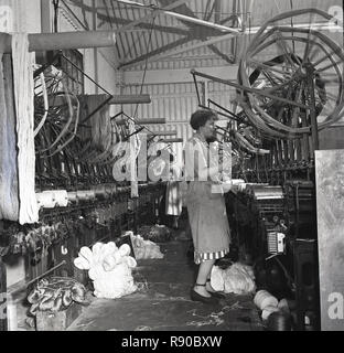 1950, historische, weibliche Arbeitnehmer stehen mit Maschinen in Weberei Herstellung von Leinen. Stockfoto