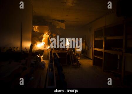 Ein 35Th Bauingenieur Squadron Feuerwehrmann fügt Starter Flüssigkeit in den Holzpaletten in einem Abbruchhaus am Misawa Air Base, Japan, 15. März 2017. Die Holzkonstruktion wurde niedergebrannt auf Abriss Kosten zu sparen. Die Fazilität nahm etwa zwei Stunden von der ersten Zündung zur totalen Zerstörung zu brennen. Es war immer noch aktiv Brennen (schwelbrand) für weitere 12 bis 18 Stunden nach. Die 35Th Fighter Wing Feuerwehrmänner Zug sowohl lokale als auch globale Missionen zu erfüllen. Stockfoto