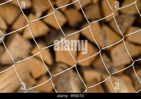 Monotone Metallgitter Zellen im Vordergrund und eine Vielfalt von Brennholz auf einen unscharfen Hintergrund Stockfoto