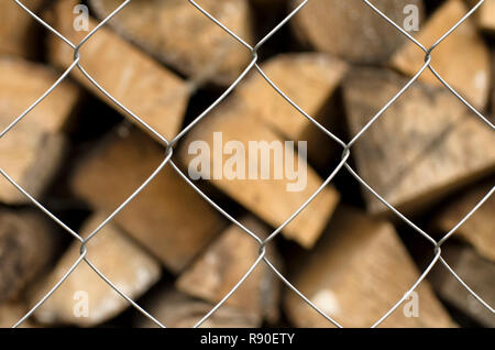Monotone Metallgitter Zellen im Vordergrund und eine Vielfalt von Brennholz auf einen unscharfen Hintergrund Stockfoto