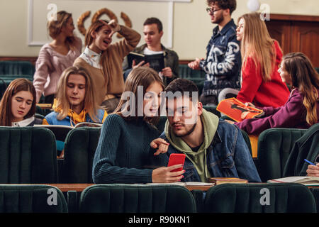 Die Gruppe der fröhliche Studenten in einem Hörsaal sitzen, bevor Lektion. Die Bildung, Universität, Vorlesung, Menschen, Institut, Hochschule, Studium, Freundschaft und Kommunikation Konzept Stockfoto