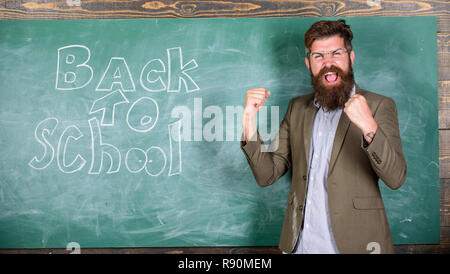 Einladung zum Wissen Tag feiern. Lehrer erste Lektion nach den Ferien beginnen. Laden zur Schule. Lehrer oder Erzieher begrüßt Studenten während steht in der Nähe der Tafel mit Inschrift zurück in die Schule. Stockfoto