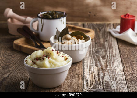 Gesunde vegetarische Mahlzeit auf pflanzlicher Basis. Kartoffelpüree und hausgemachte eingelegte Pilze. Sea kale Salat mit roten Zwiebeln in Weiß rustikal Becher Stockfoto