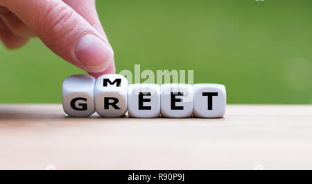 Hand dreht einen Würfel und Änderungen das Wort 'Meet' zu 'Grüße' Stockfoto